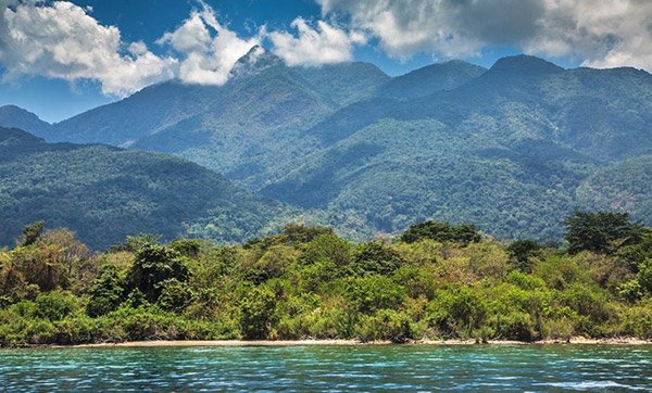 The dramatic tall peak of Mount Nkungwe towering high above the blue waters of Lake Tanganyika
