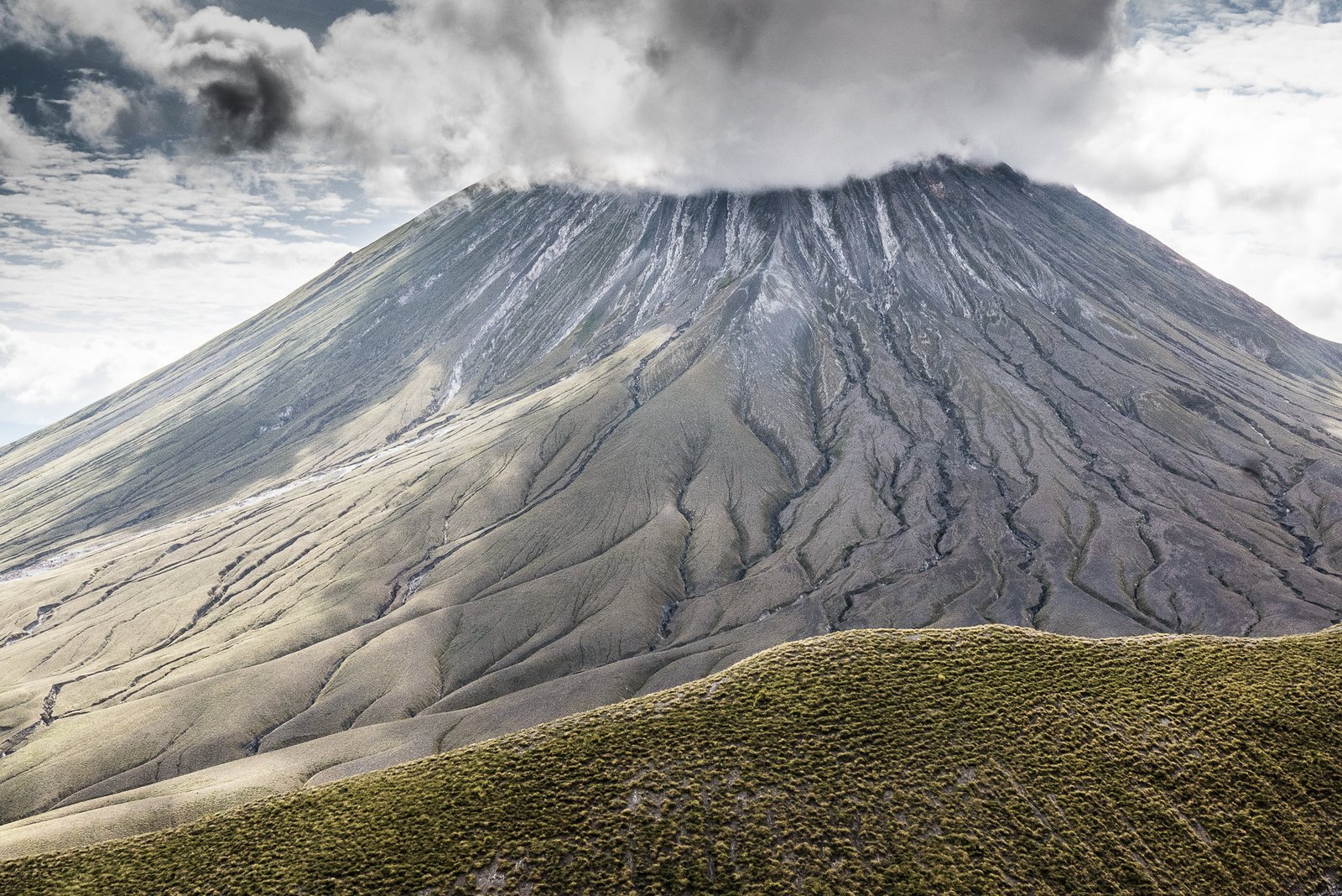 Aerial look down inside the smoking active volcanic crater of Ol Doinyo Lengai showcasing silver natrocarbonatite ash vents
