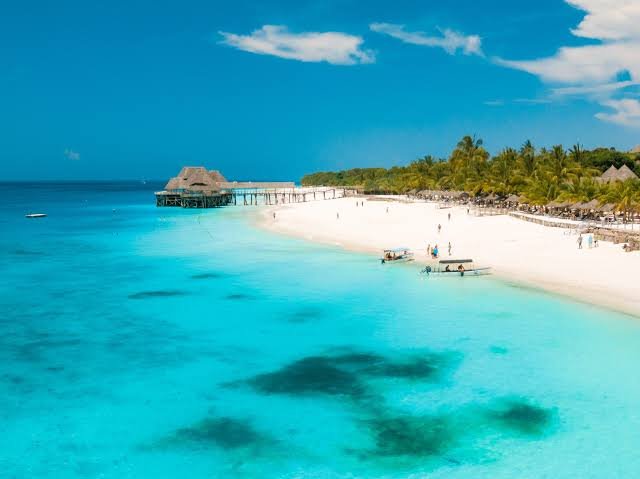 Beautiful direct flight aircraft heading over the blue ocean water channels connecting to Zanzibar island